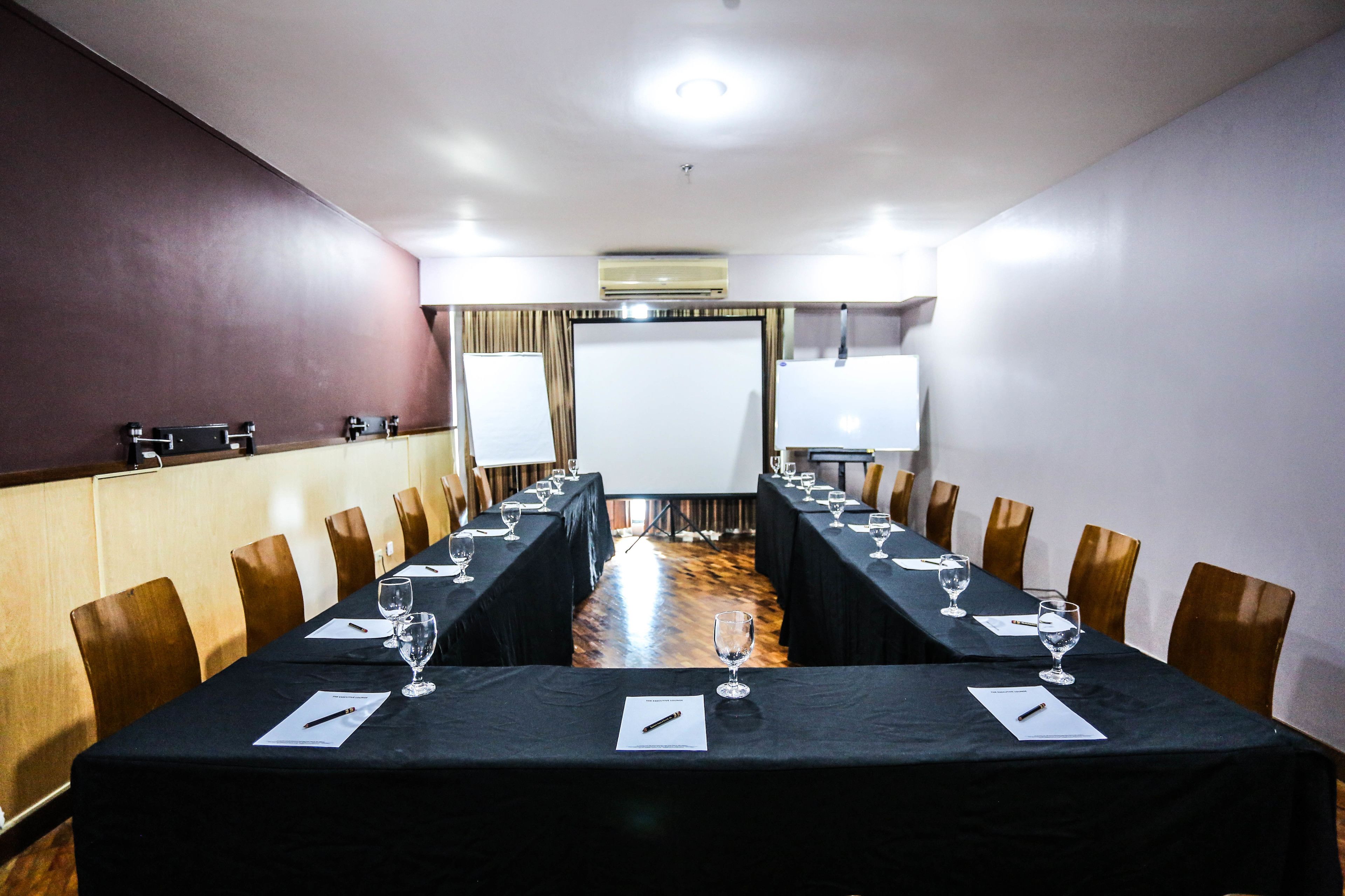A conference room with a long table, chairs, and a whiteboard.