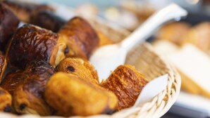 A basket filled with various baked goods, including pastries and bread, with a white spoon inside. - Ténéo Apparthotel Talence - Centre (Talence)