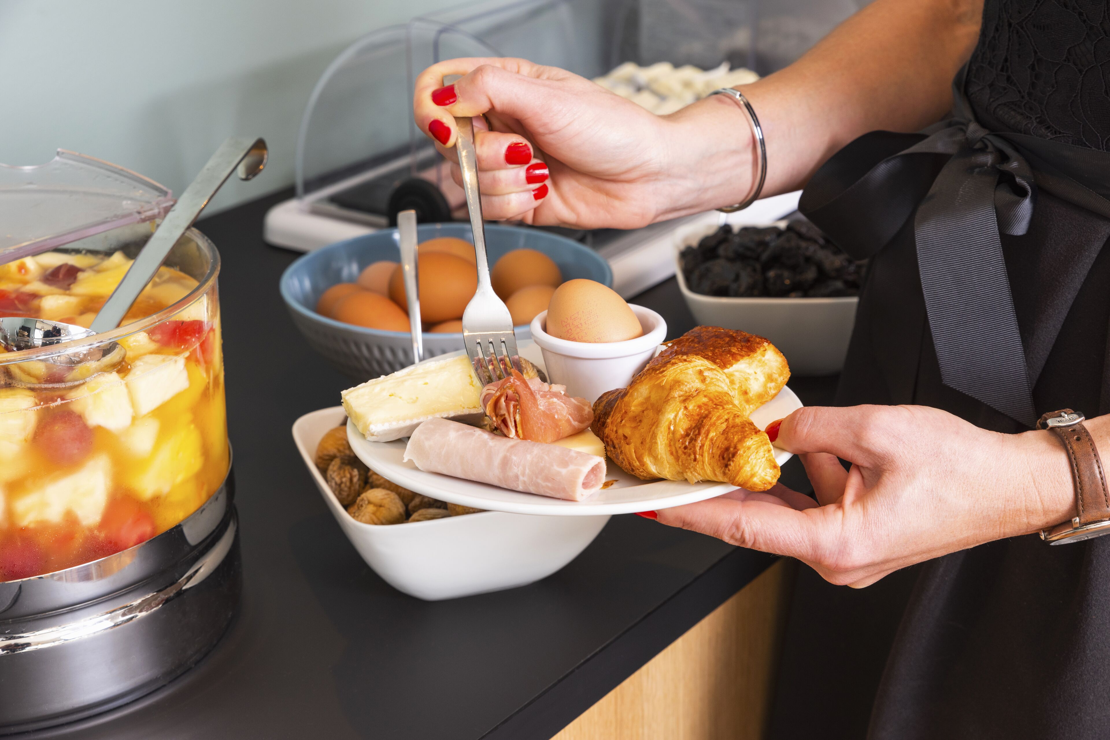 Un buffet de petit-déjeuner proposant une variété d’aliments, notamment des œufs, des viennoiseries et des fruits.