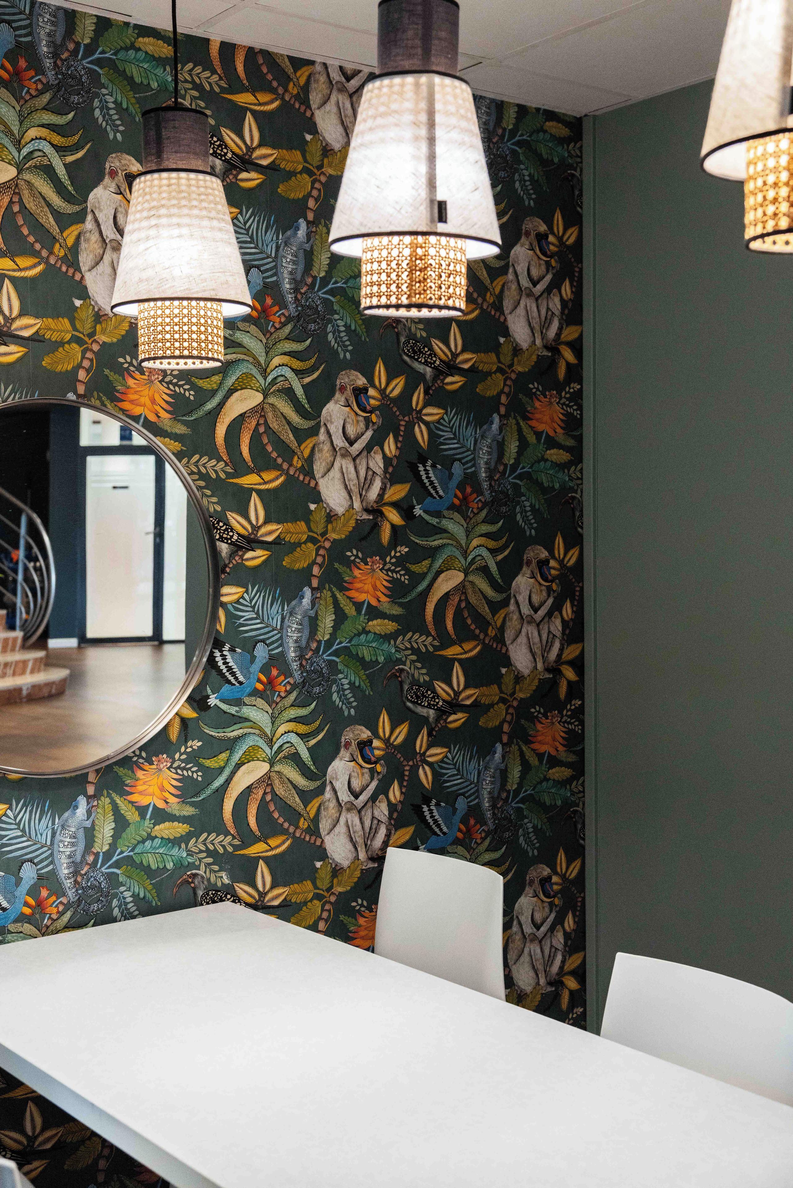 Una habitación con una mesa larga, papel tapiz estampado y lámparas colgantes.