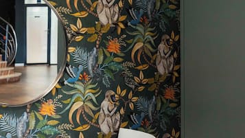 Una habitación con una mesa larga, papel tapiz estampado y lámparas colgantes.