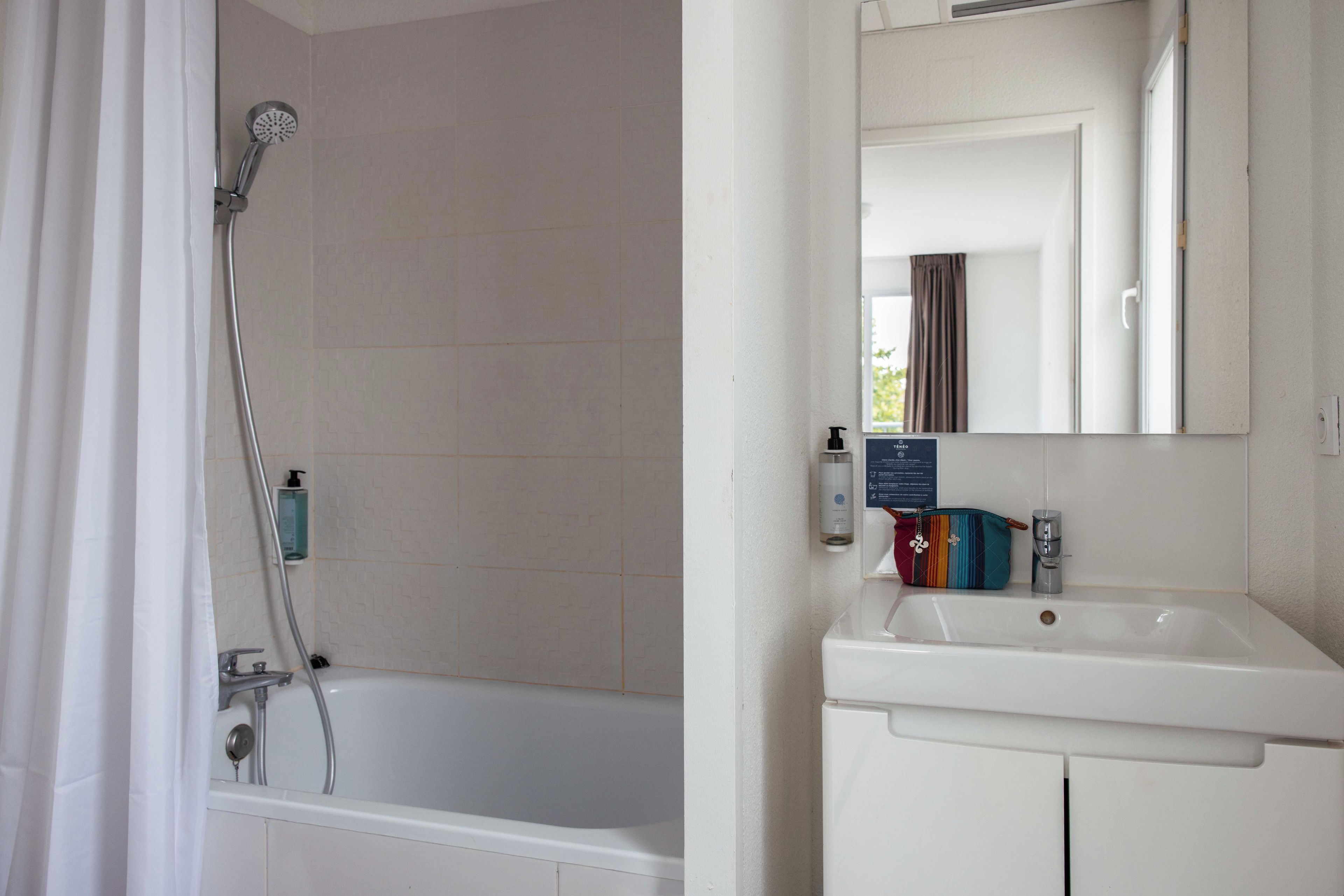Un baño con bañera, ducha, lavamanos y espejo.