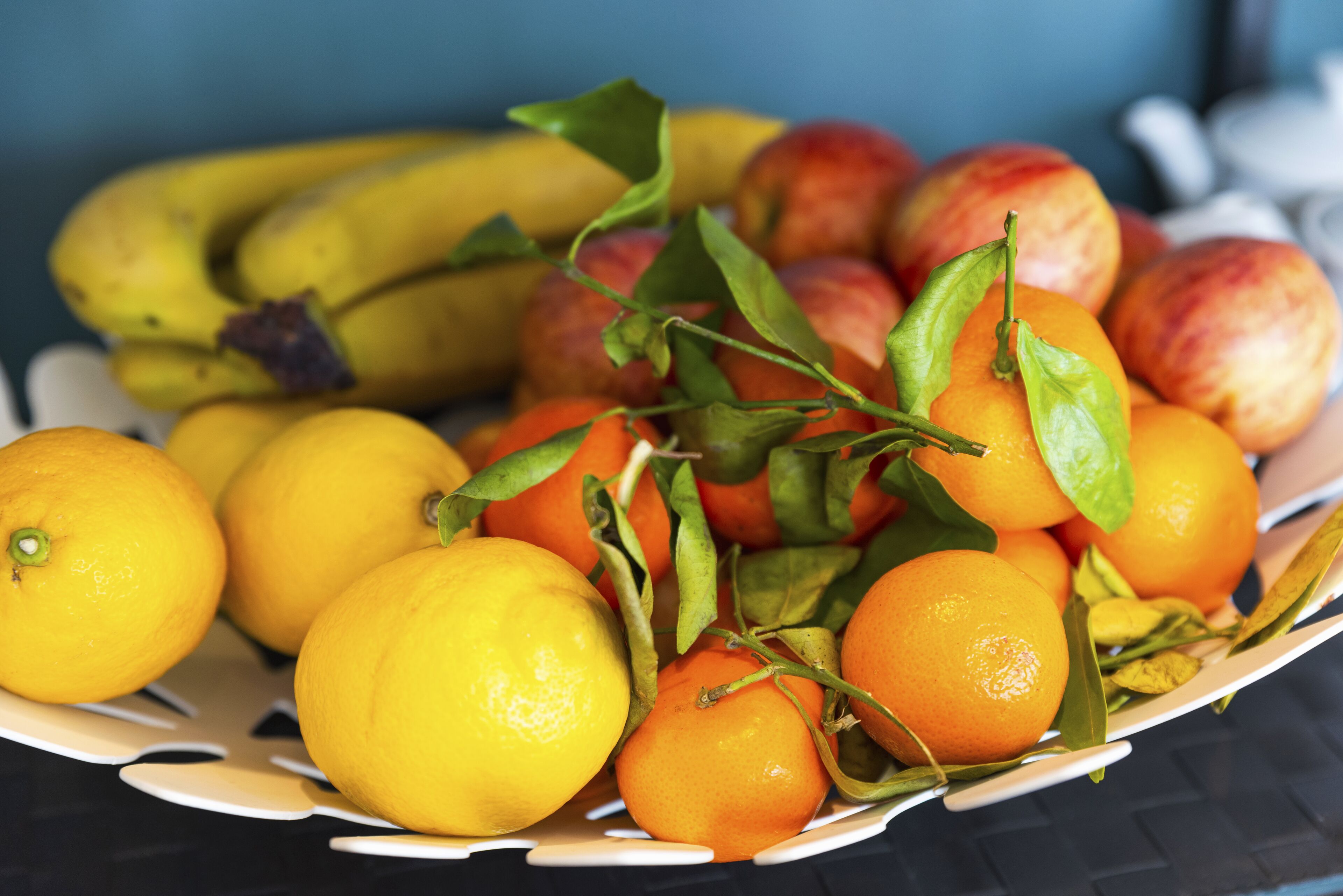 A basket of fruits including oranges, bananas, and peaches.