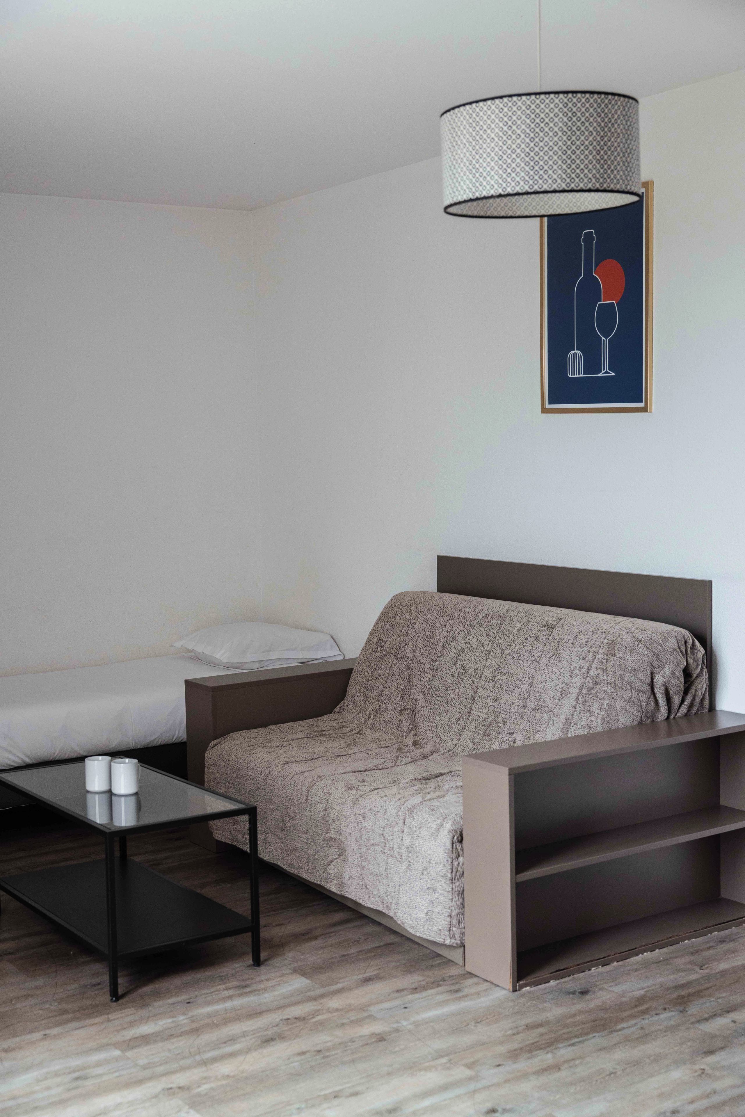 A modern bedroom with a bed, bedside table, and a hanging lamp.