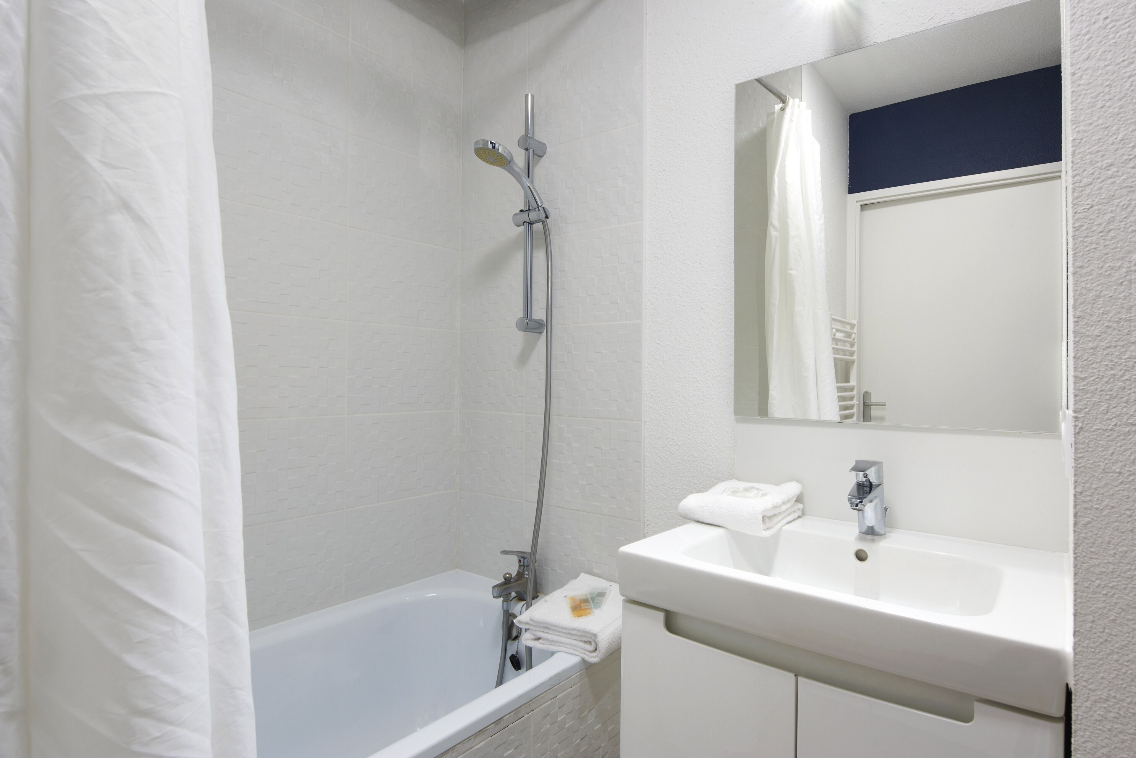 Un baño con bañera, ducha y lavamanos con espejo.