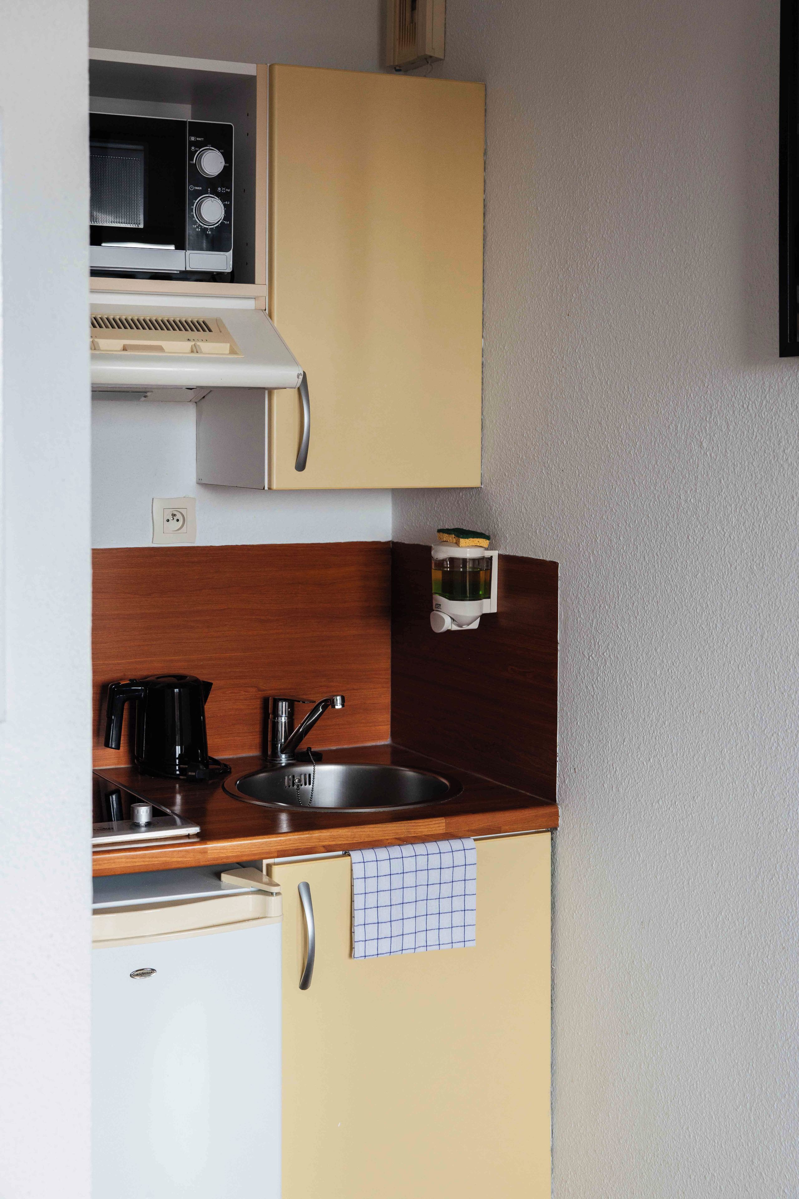 A compact kitchenette with a microwave, a coffee maker, a sink, and a small refrigerator.