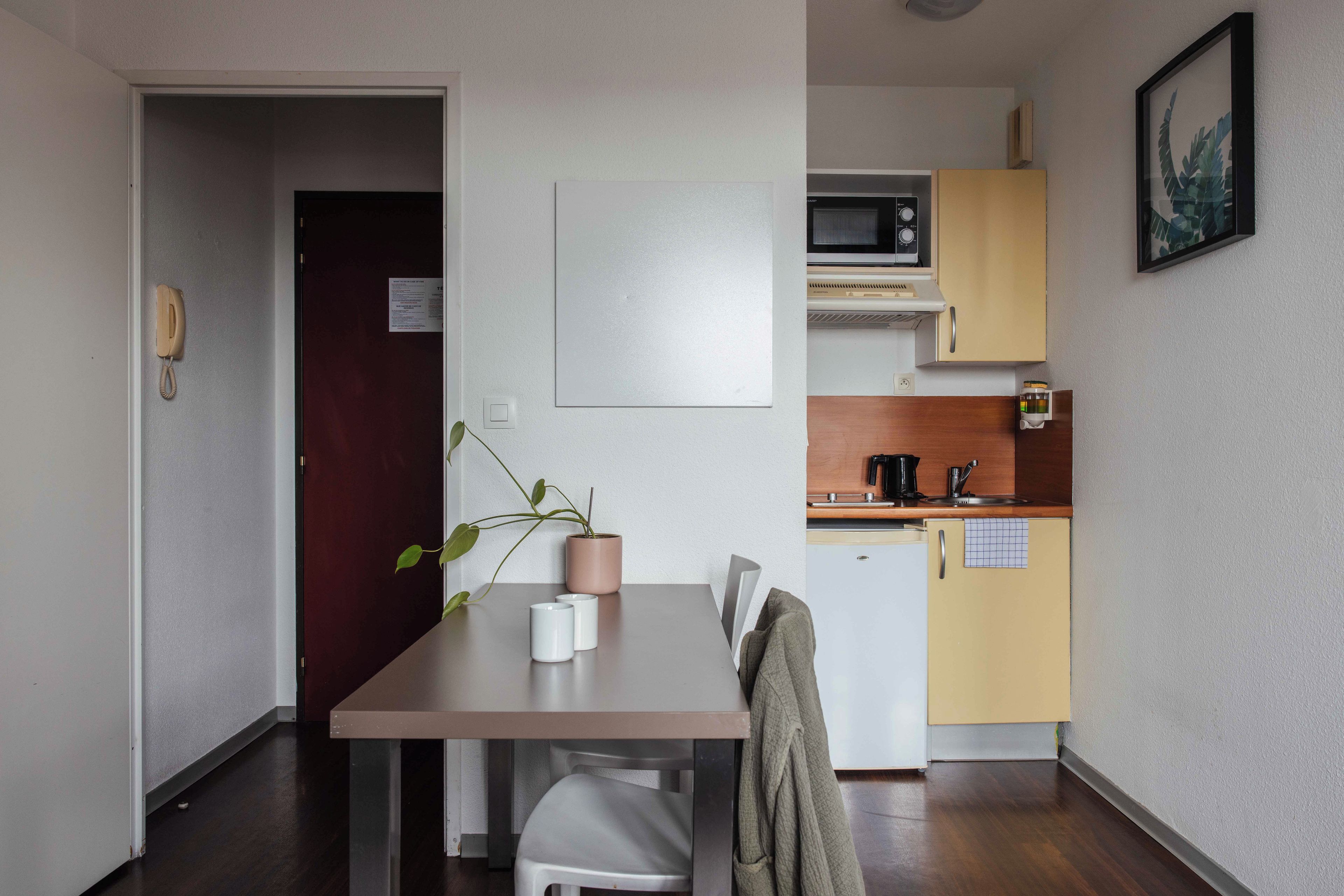 Una cocina compacta con microondas, un refrigerador pequeño y un lavamanos.