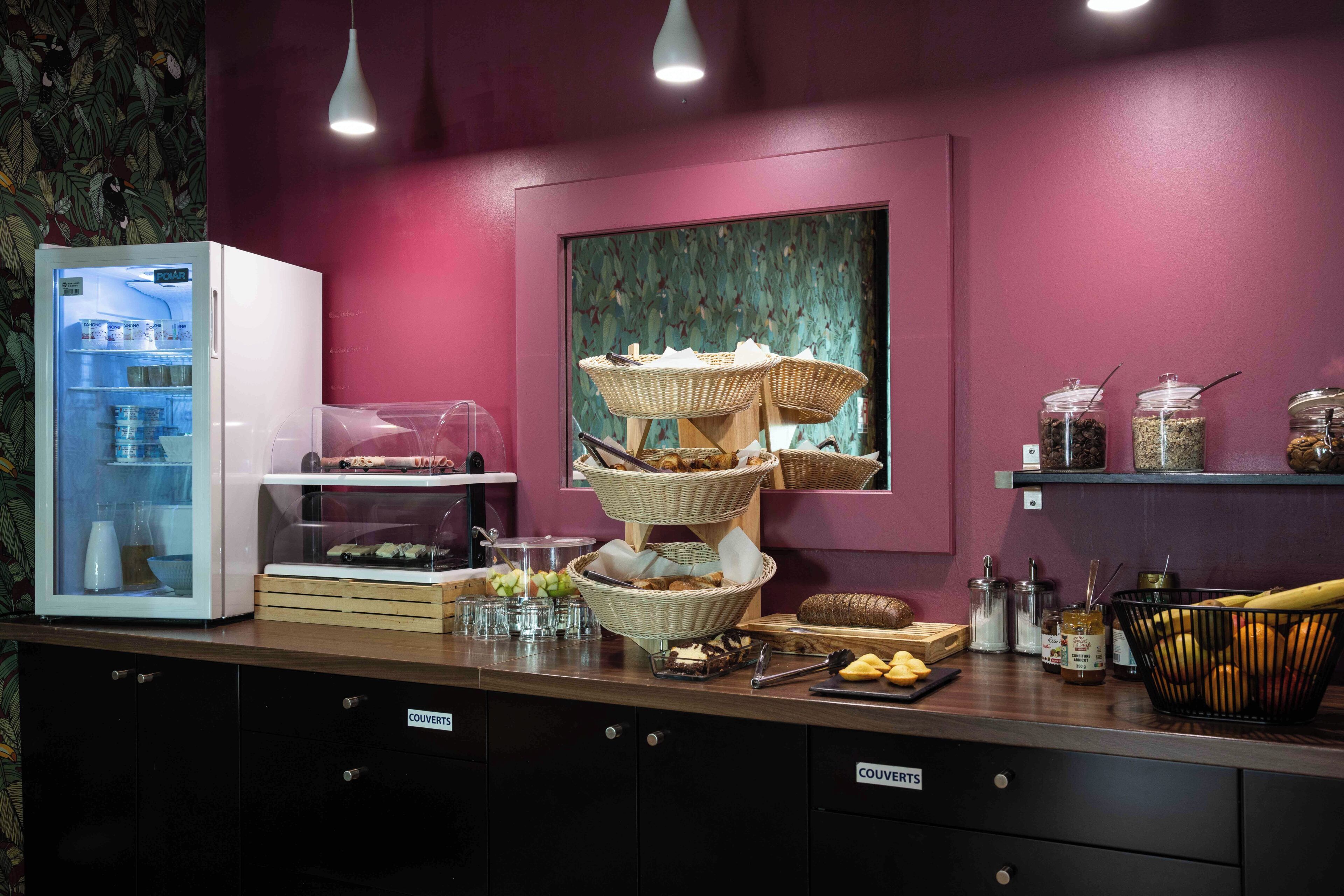 A buffet setup with a refrigerator, baskets of bread, and various food items.
