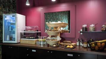 A buffet setup with a refrigerator, baskets of bread, and various food items.