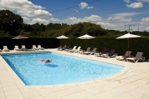 A swimming pool with lounge chairs and umbrellas, surrounded by a hedge and trees. - Golf de Saint Junien (Saint-Junien)