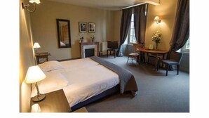 A hotel room with a bed, bedside lamps, a small table with chairs, a fireplace, and a window with curtains. - Golf de Saint Junien (Saint-Junien)