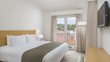 Une chambre d’hôtel avec un grand lit, un bureau et une télévision.