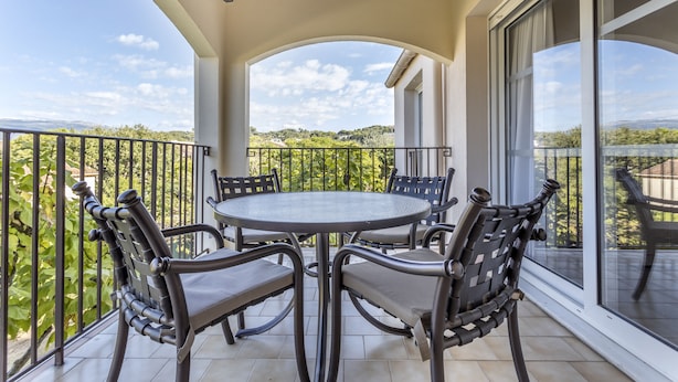 A balcony with a round table and four chairs, offering a view of greenery and distant hills. - Le Club Mougins (Mougins)