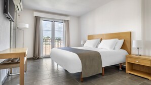A hotel room with a bed, a desk, a TV, and a balcony with curtains. - Le Club Mougins (Mougins)