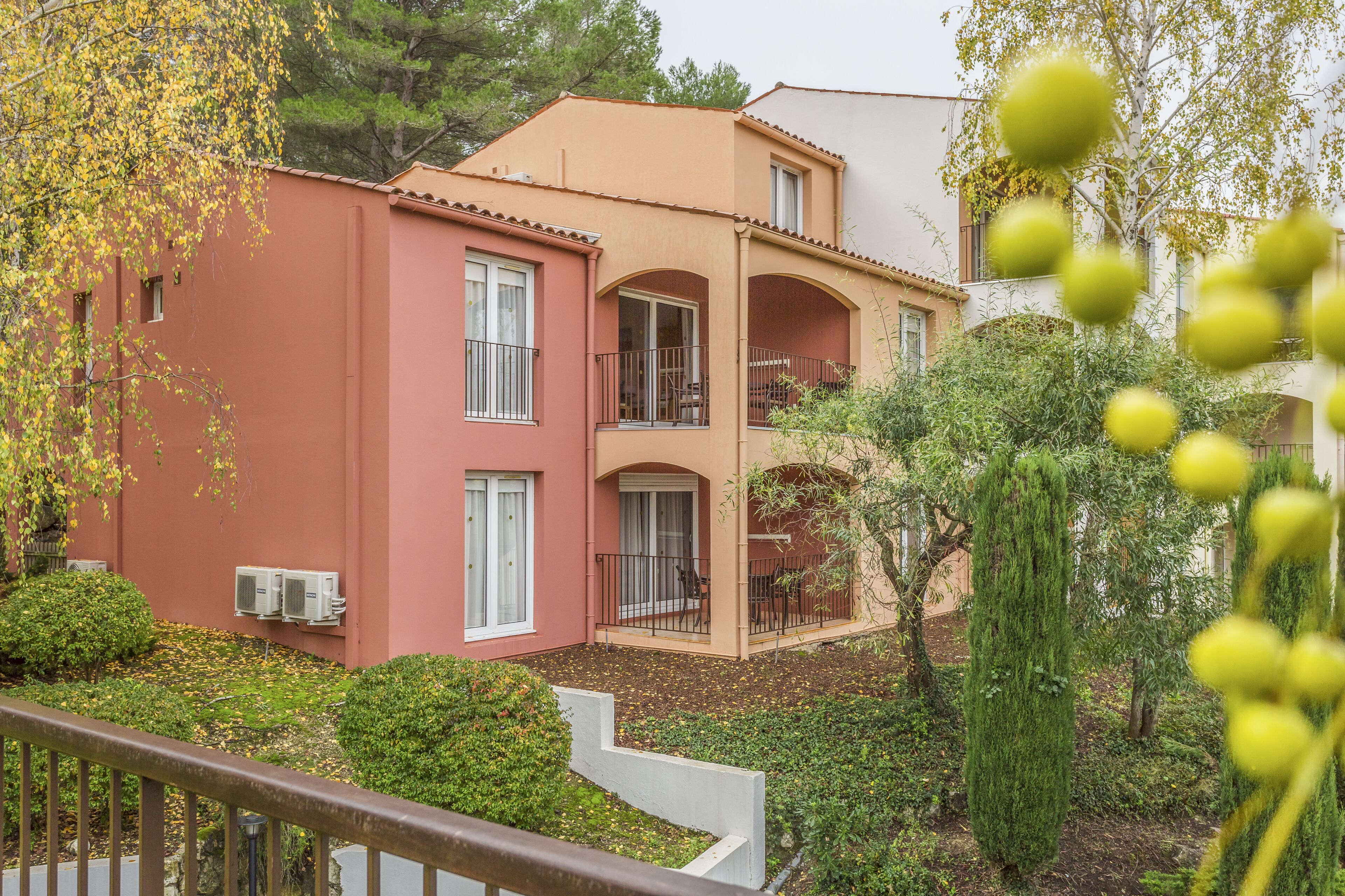 A two-story building with balconies and a garden area.