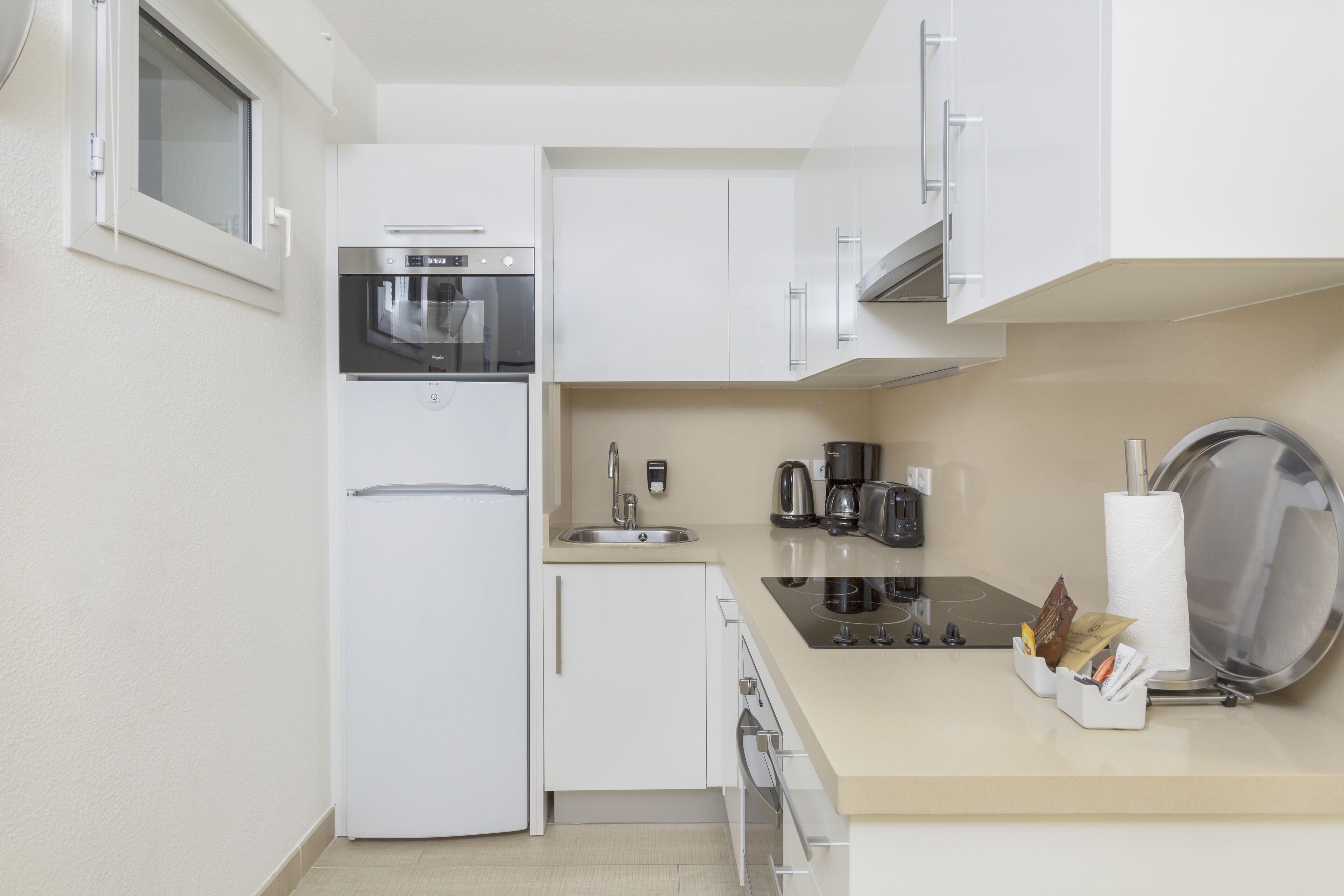 A compact kitchen with a built-in microwave, a coffee maker, and a kettle.