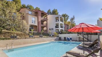 En sÀsongsöppen utomhuspool, parasoller och solstolar