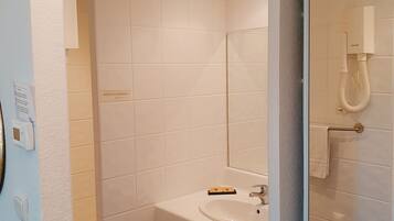 Un baño moderno con un lavamanos blanco, cabina de ducha con paredes de vidrio y un perchero para toallas.
