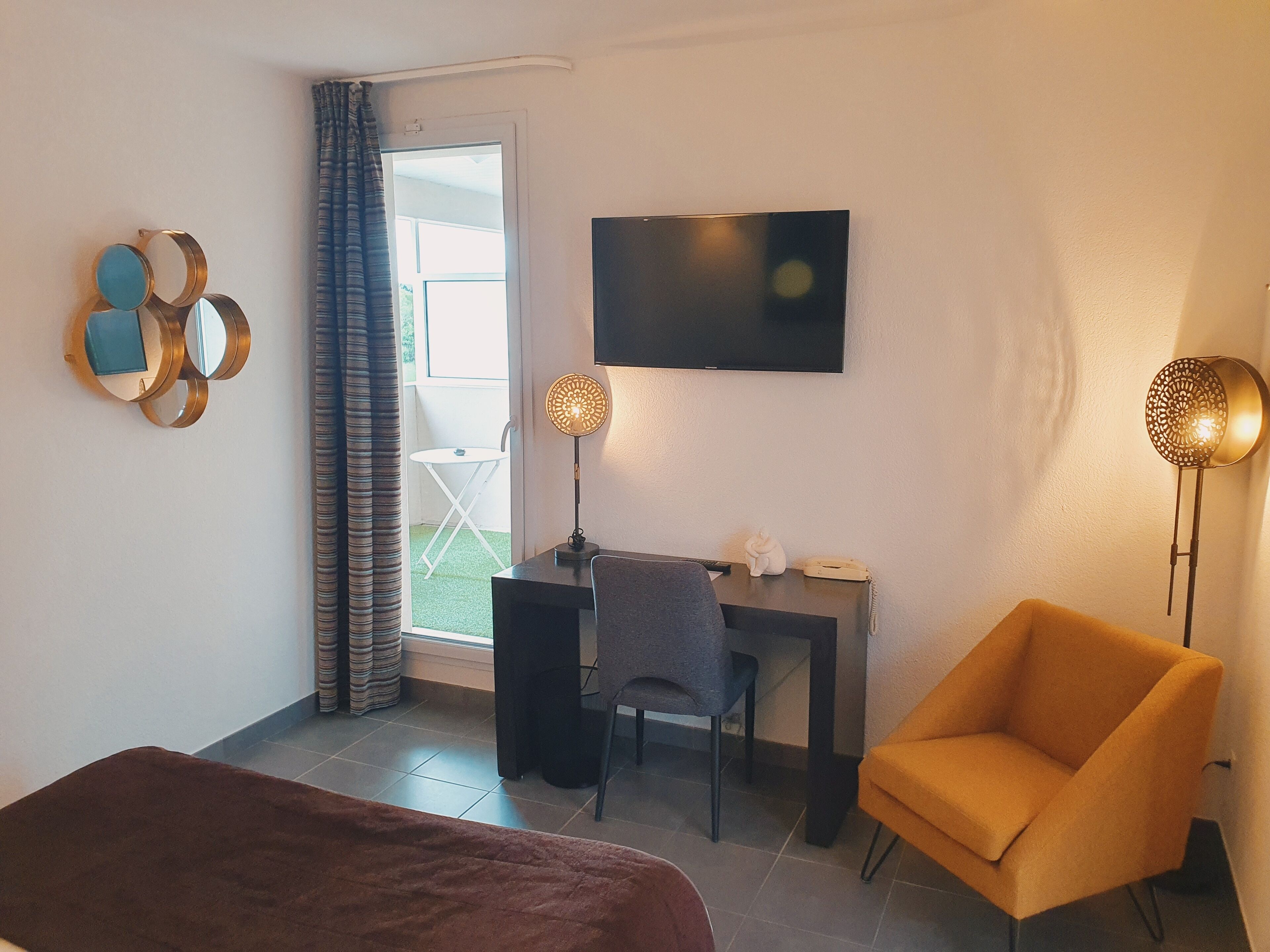 Una habitación con una cama, un escritorio, una silla, un televisor y una lámpara.