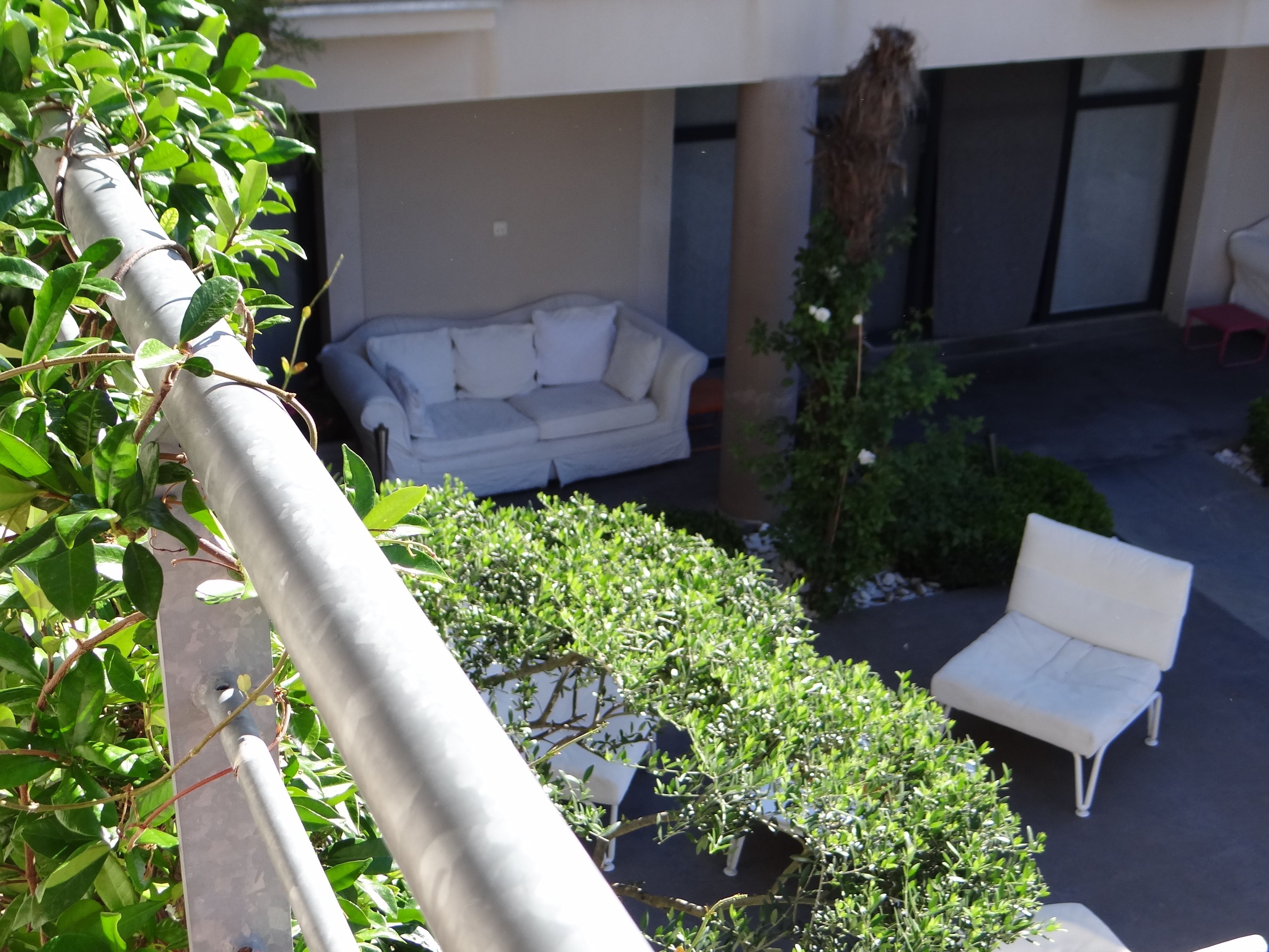 Une cour avec un canapé blanc, une chaise blanche et des plantes vertes.