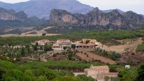 Un pueblo rural con edificios tradicionales rodeado de montañas y vegetación.