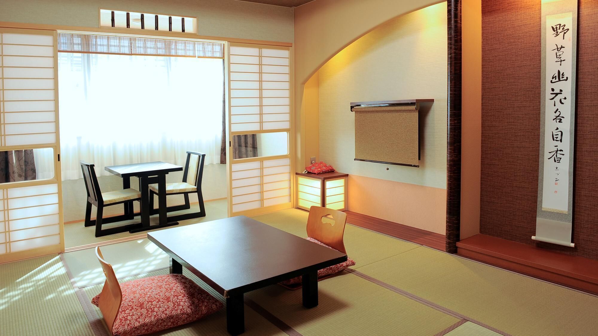 A traditional Japanese room with tatami flooring, a low table, chairs, and sliding doors.