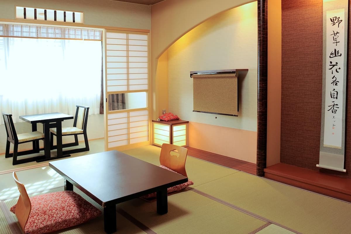 A traditional Japanese room with tatami flooring, a low table, chairs, and sliding doors.
