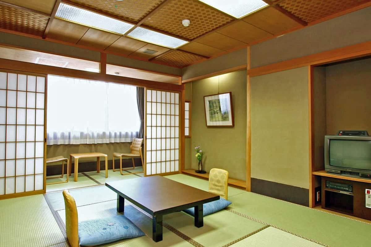 A traditional Japanese room with tatami flooring, a low table, and a television.