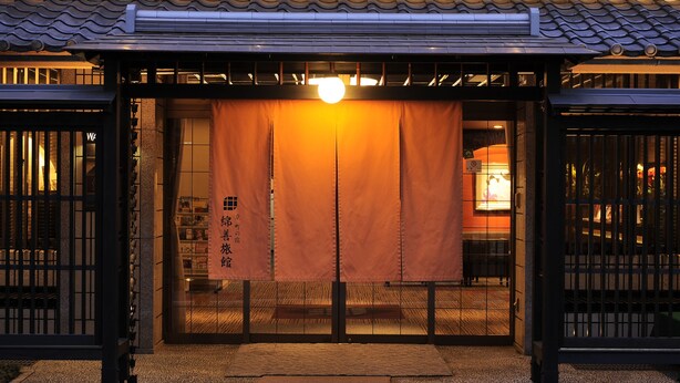 De ingang van een traditioneel Japans gebouw, met een schuifdeur en een hangende lantaarn.