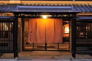 Entrada de un edificio japonés tradicional con puerta corrediza y un farol colgante.