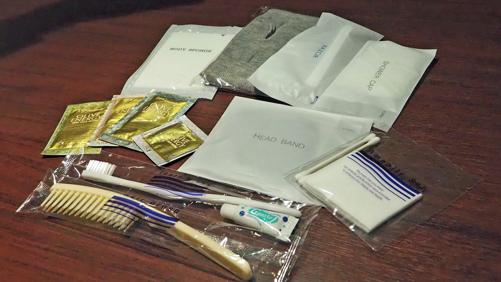 Toiletries including a toothbrush, toothpaste, and body spray on a wooden surface.