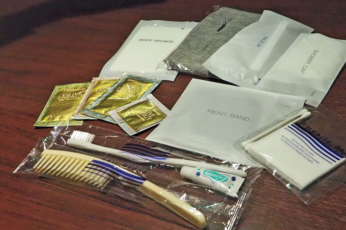 Toiletries including a toothbrush, toothpaste, and body spray on a wooden surface.