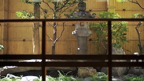 Een traditionele Japanse tuin met stenen lantaarns, bamboebeschutting en een vijver met koi.