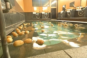 Une piscine dotée de plusieurs éléments décoratifs aquatiques et d’un mur recouvert de carreaux.