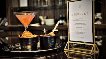 Zona de bar con un menú titulado "MIXOLOGY" que presenta bebidas como Manhattan, Old Fashioned, Martini Dirty y Espresso Martini.