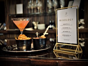 A bar area with a menu titled "MIXOLOGY" listing drinks like Manhattan, Old Fashioned, Dirty Martini, and Espresso Martini. - L'Hermitage Hotel (Vancouver)