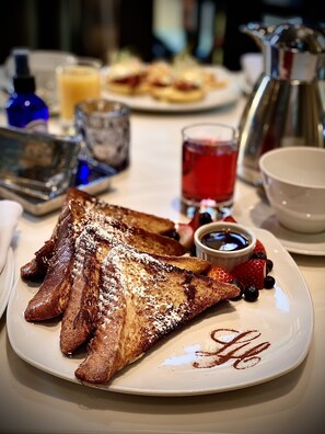 A breakfast plate with French toast, strawberries, blueberries, and a small cup of syrup. - L'Hermitage Hotel (Vancouver)