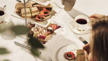 A table set with various food items, including sandwiches, pastries, and a vase with flowers.
