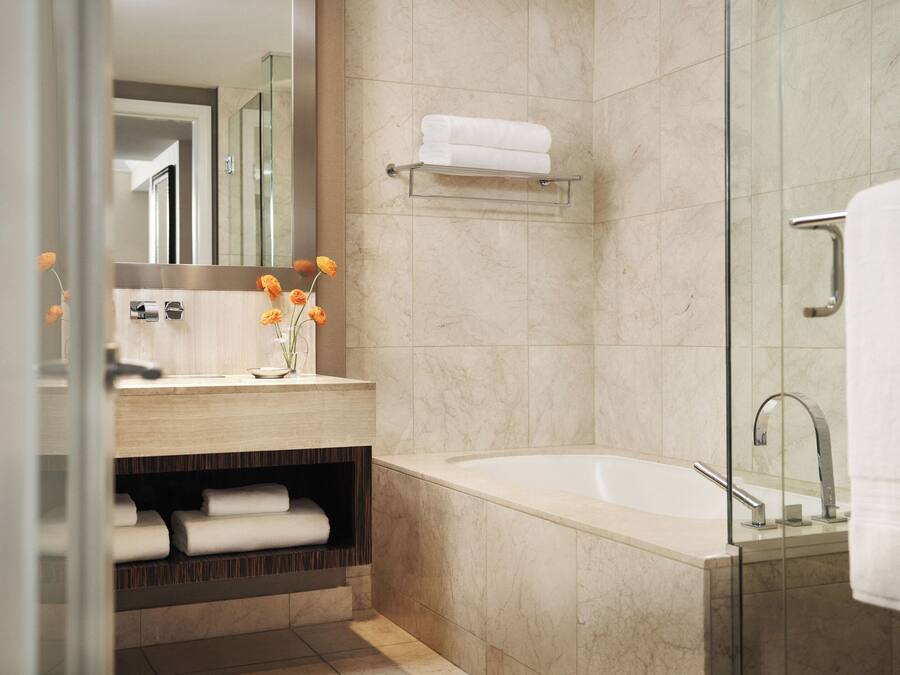 A modern bathroom with a bathtub, a glass shower enclosure, a vanity with a mirror, and a shelf with towels.