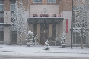 Entrada de un hotel con fachada cubierta de nieve y un letrero que dice 'LIHERMITAGE'.