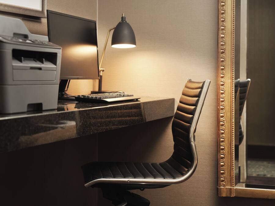 A modern office desk with a computer, a lamp, and a chair.