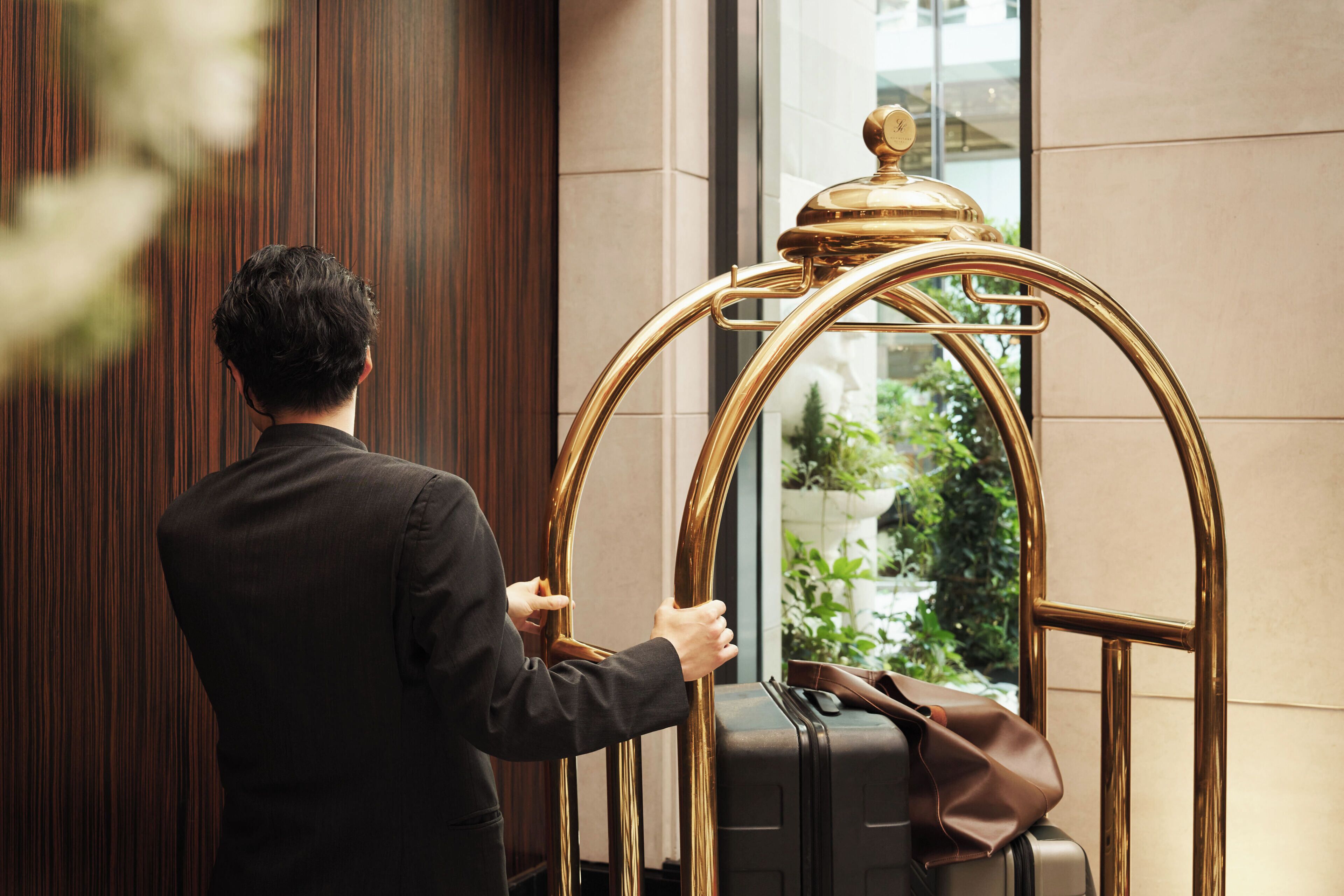 A person in a black suit interacting with a golden, ornate elevator door.