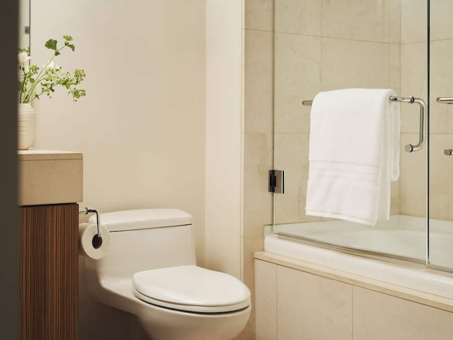 Ein Badezimmer mit Toilette, einer Duschkabine aus Glas und einem Handtuchhalter.