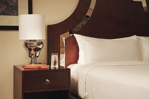 A hotel room with a bed, a nightstand with a lamp, and a glass of water.