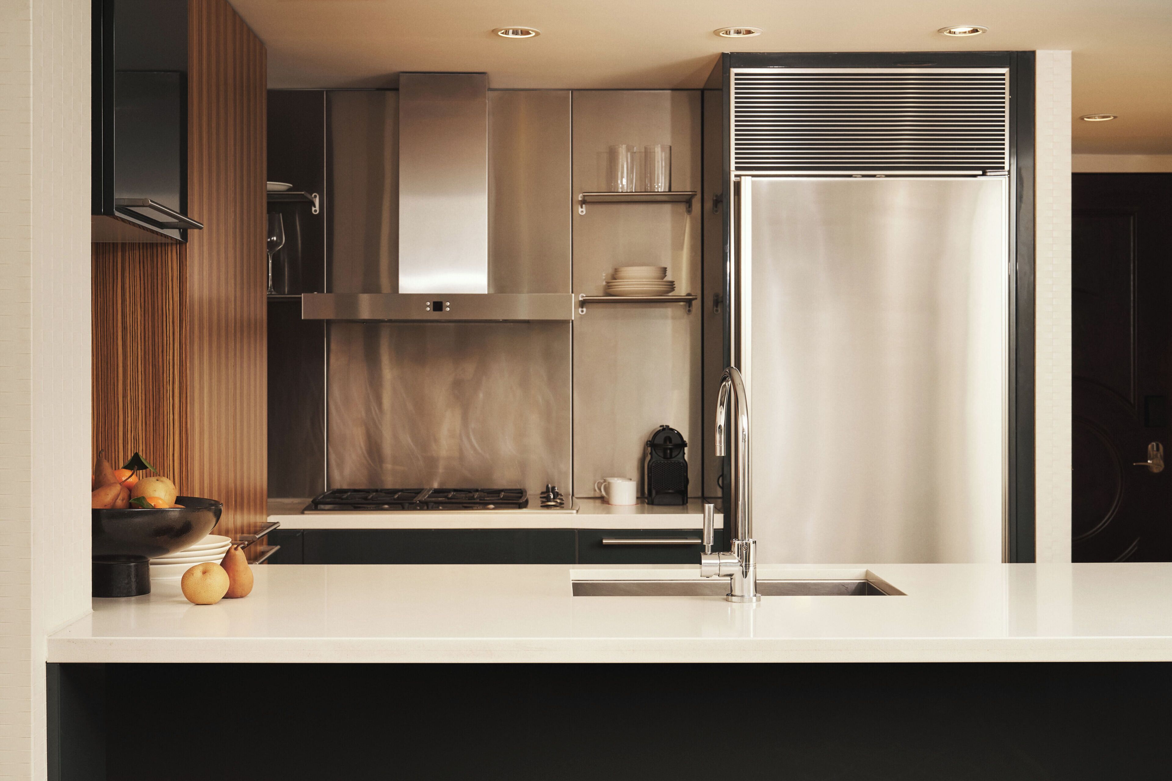 A modern kitchen with a stainless steel refrigerator, a built-in oven, and a sink.