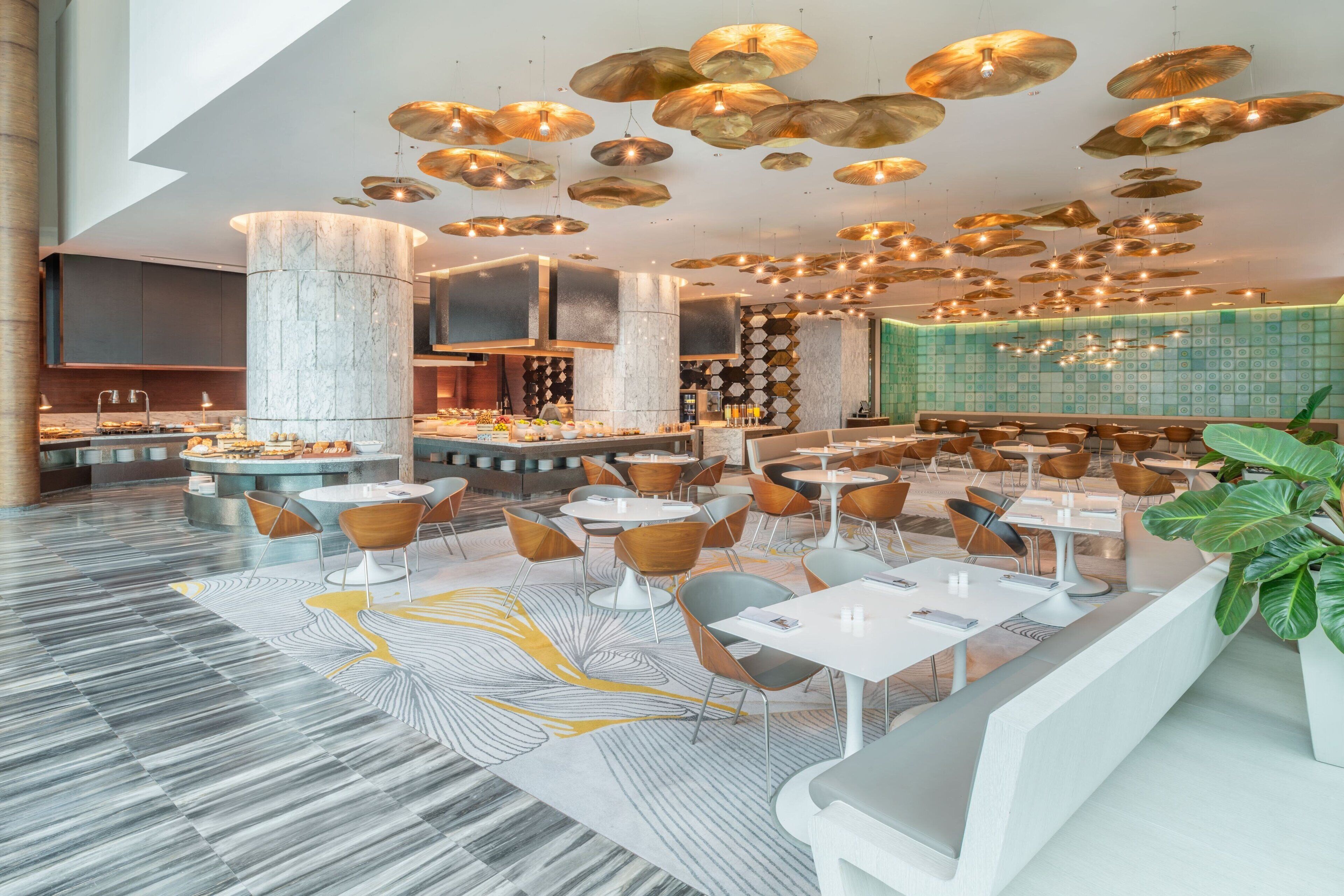 Un restaurante moderno con barra central, zonas de estar y suelo estampado.