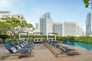 Una piscina al aire libre, sombrillas, sillones reclinables de piscina