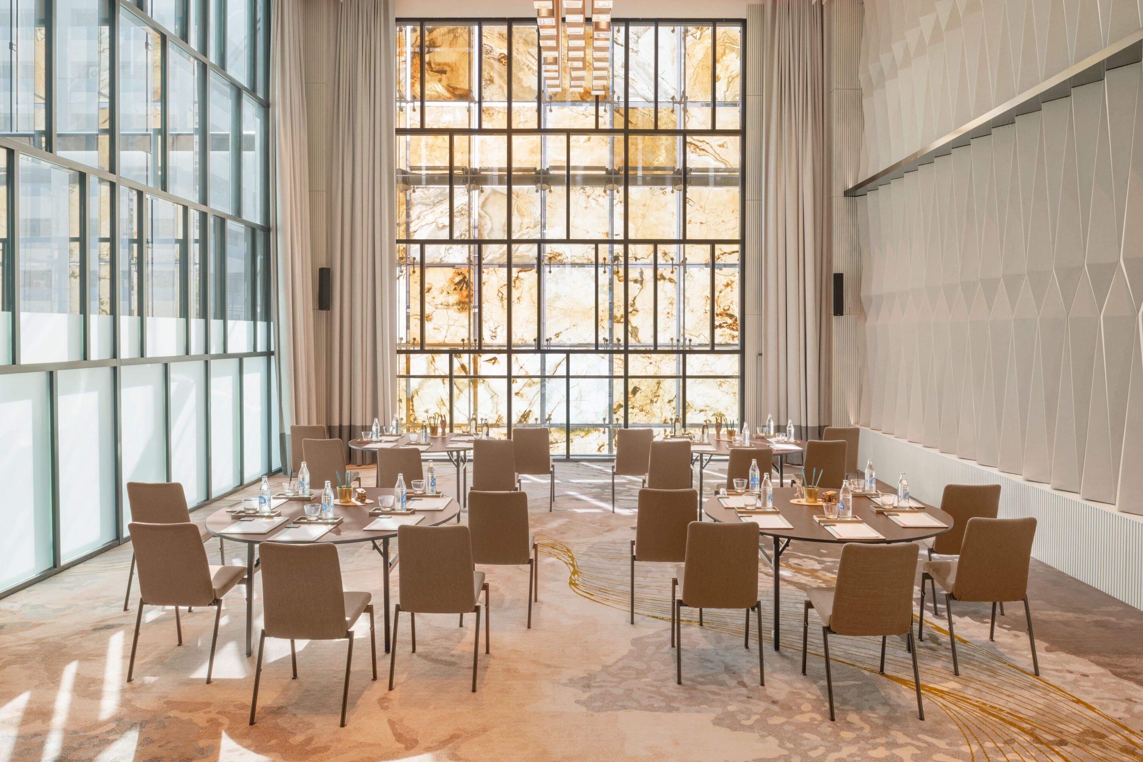 A conference room with a large window, multiple tables, and chairs arranged for meetings.