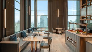 A modern hotel lobby with a seating area, a bar, and large windows offering city views. - Le Meridien Bangkok (Bangkok)