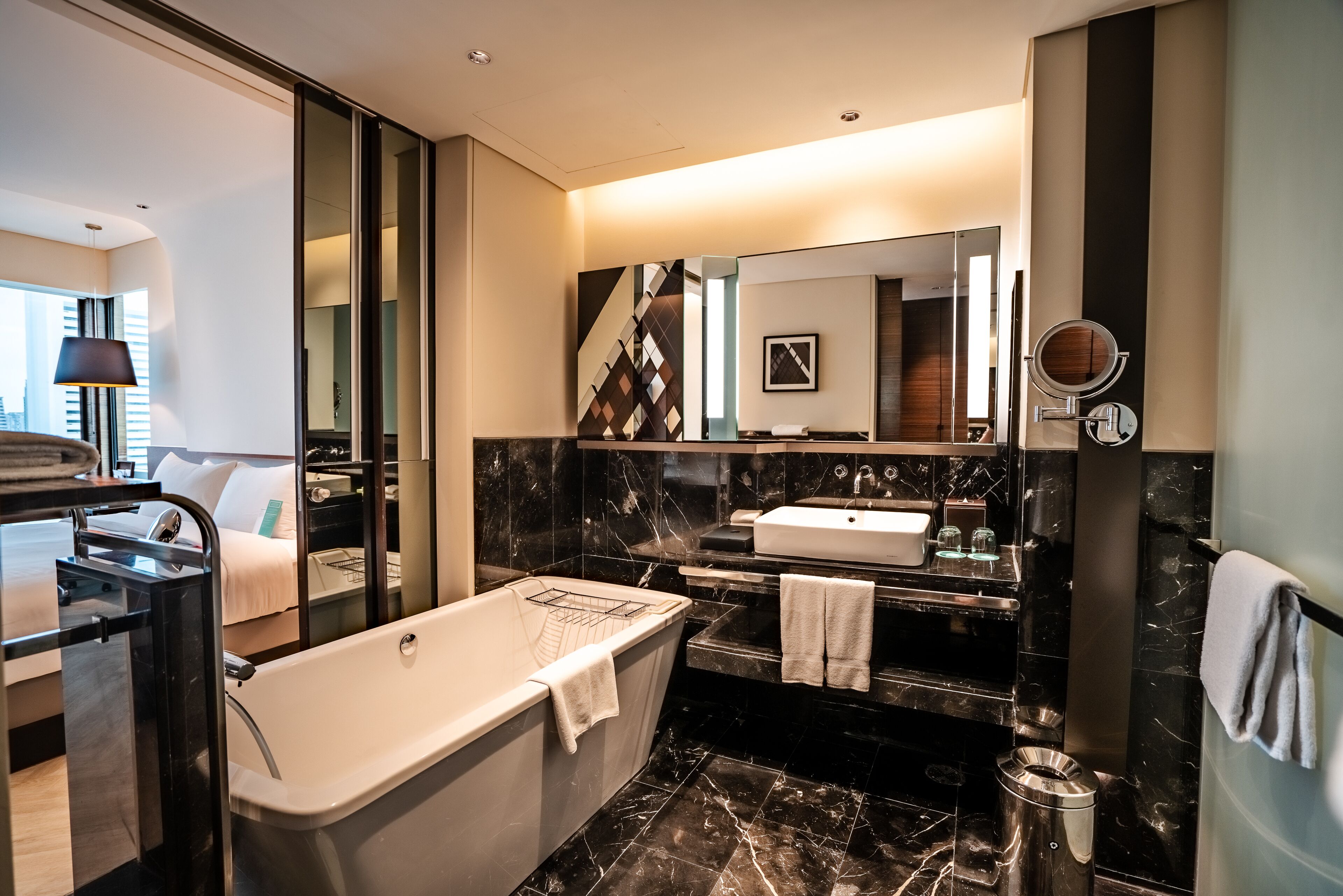 A modern bathroom with a freestanding bathtub, a large mirror, a sink, and a toilet.